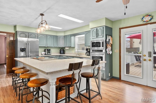 411 S High St, Belleville, IL 62220 - kitchen featuring appliances with stainless steel finishes, a sink, light wood-style floors, a breakfast bar, and a center island