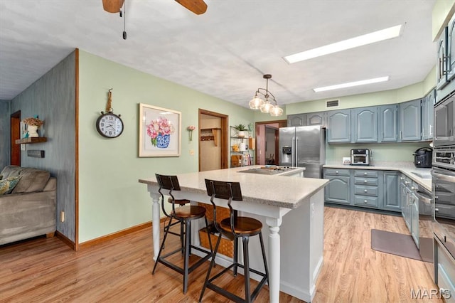 411 S High St, Belleville, IL 62220 - kitchen with stainless steel appliances, a center island, light countertops, and light wood-type flooring