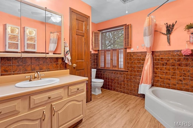 411 S High St, Belleville, IL 62220 - full bath with tile walls, wainscoting, wood finished floors, toilet, and a bath