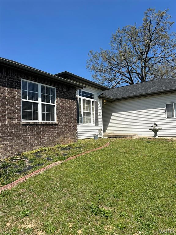 142 Oregon Ln, Kimberling City, MO 65686 - view of home's exterior featuring a lawn and brick siding