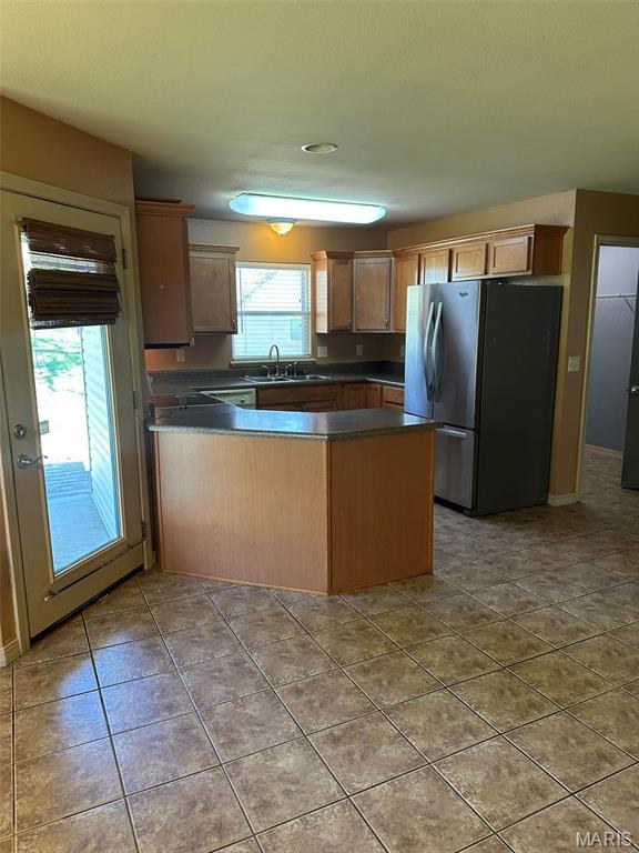142 Oregon Ln, Kimberling City, MO 65686 - kitchen featuring freestanding refrigerator, dark countertops, a peninsula, tile patterned floors, and a sink
