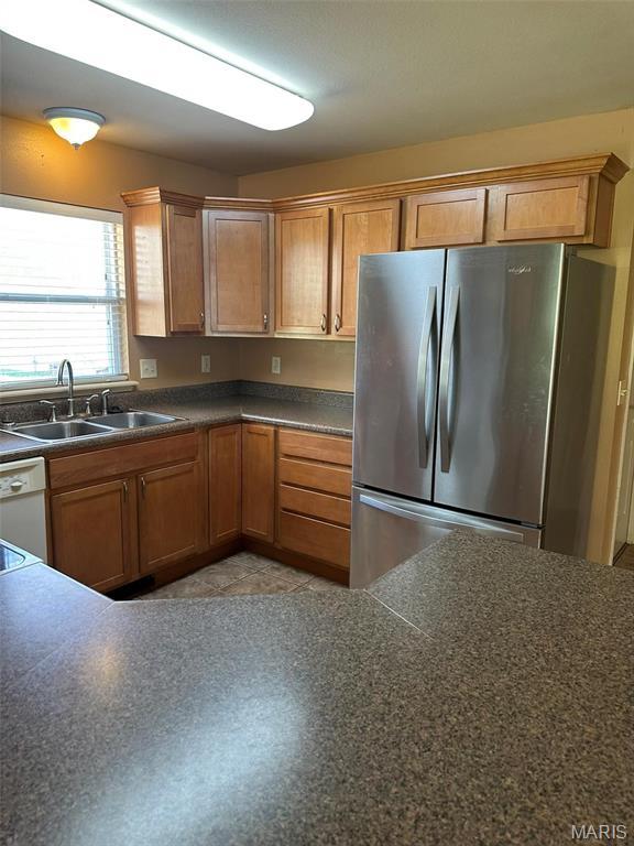 142 Oregon Ln, Kimberling City, MO 65686 - kitchen with freestanding refrigerator, a sink, dark countertops, white dishwasher, and brown cabinetry