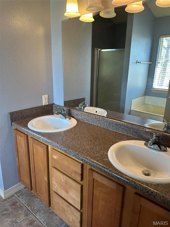 142 Oregon Ln, Kimberling City, MO 65686 - bathroom with double vanity, a shower stall, a garden tub, tile patterned flooring, and a textured wall