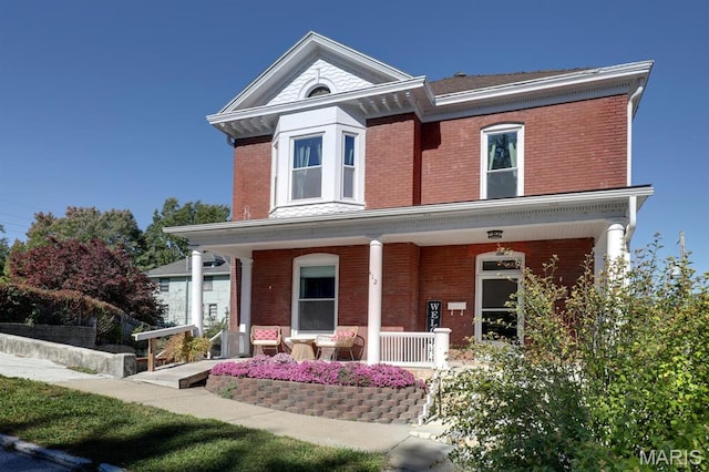 view of front facade with brick siding and a porch