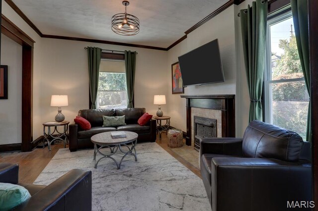 living area featuring wood finished floors, plenty of natural light, a tile fireplace, ornamental molding, and baseboards