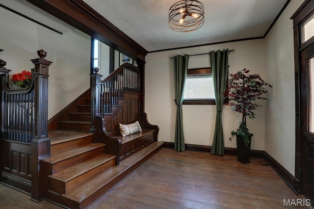foyer featuring ornamental molding, wood finished floors, stairway, a chandelier, and baseboards