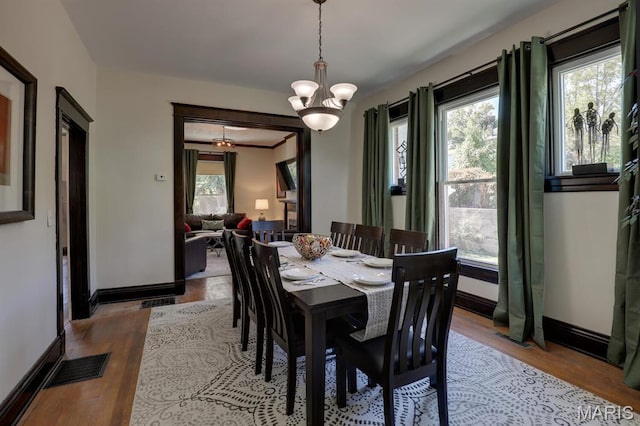 dining area with baseboards, a chandelier, and wood finished floors
