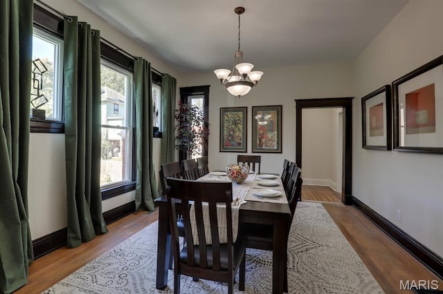dining room featuring healthy amount of natural light, a chandelier, wood finished floors, and baseboards