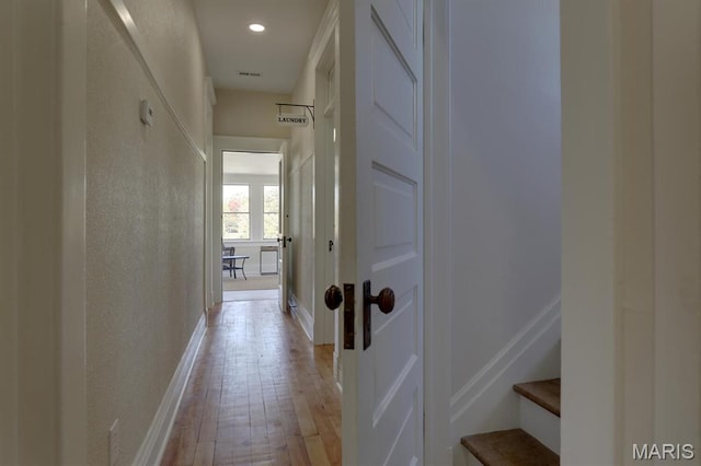 hall featuring light wood-type flooring, baseboards, and recessed lighting