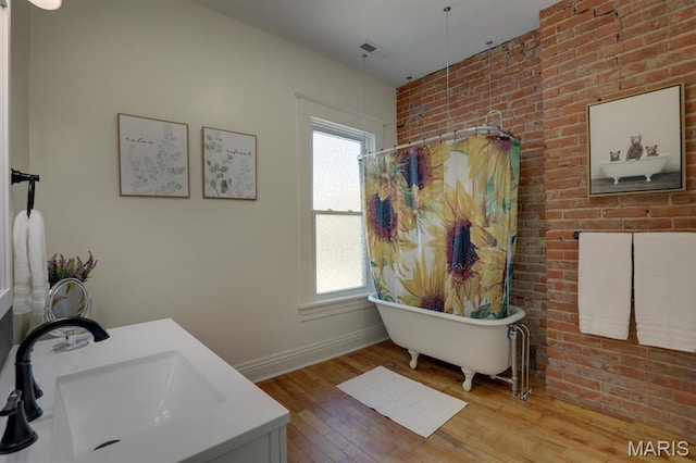 full bathroom featuring a sink, wood finished floors, a freestanding bath, baseboards, and a shower with curtain