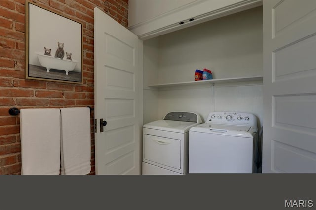laundry area with brick wall and washing machine and dryer