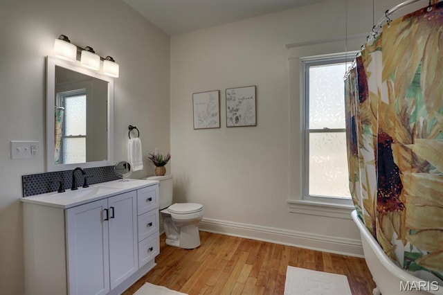 bathroom with wood finished floors, toilet, baseboards, vanity, and curtained shower