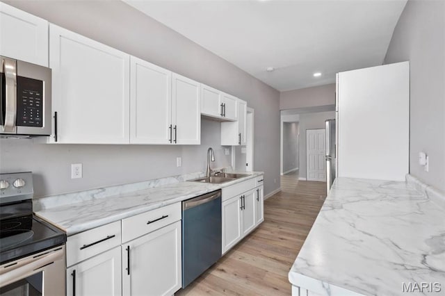 kitchen with stainless steel appliances, a sink, white cabinetry, baseboards, and recessed lighting