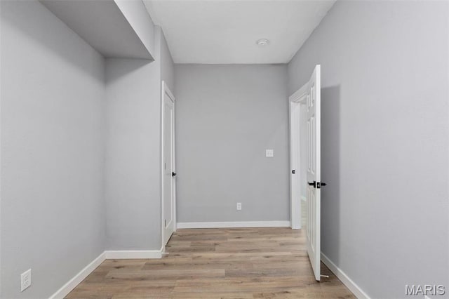 corridor with light wood-style floors and baseboards