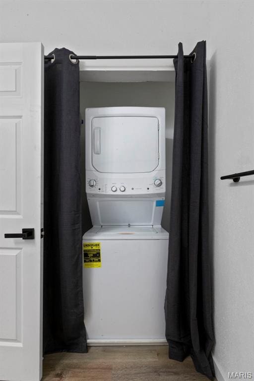 laundry room featuring stacked washing machine and dryer and wood finished floors