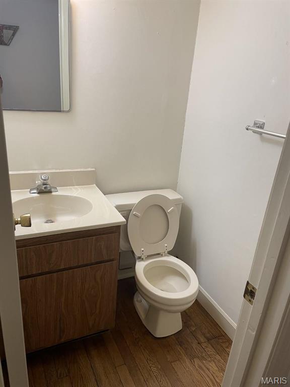 bathroom with wood finished floors, vanity, toilet, and baseboards