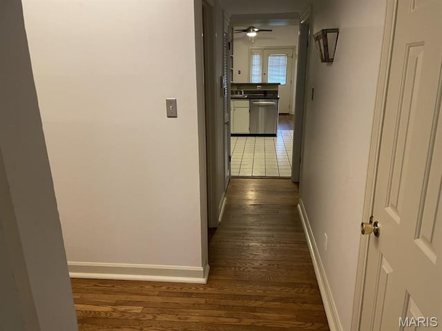 hall featuring dark wood-type flooring and baseboards