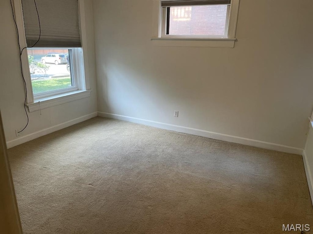 carpeted spare room featuring healthy amount of natural light and baseboards
