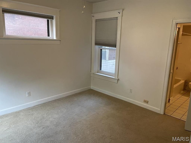 unfurnished bedroom featuring carpet flooring, multiple windows, and baseboards