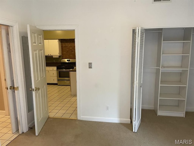 unfurnished bedroom featuring light tile patterned floors, light carpet, a closet, and baseboards