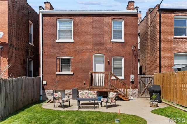 3884 Wyoming St, Saint Louis, MO 63116 - back of house featuring a chimney, brick siding, a fenced backyard, an outdoor hangout area, and a patio