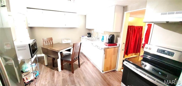 kitchen featuring electric stove, light wood-style flooring, white cabinets, and under cabinet range hood
