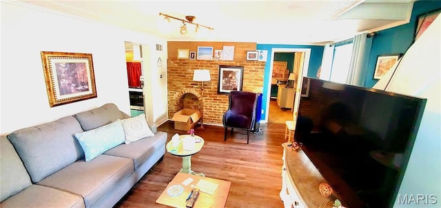 living room featuring wood finished floors and brick wall