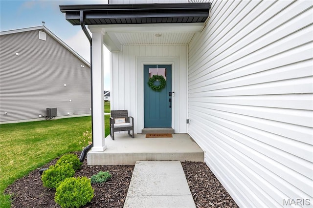 property entrance with central air condition unit, a yard, and board and batten siding