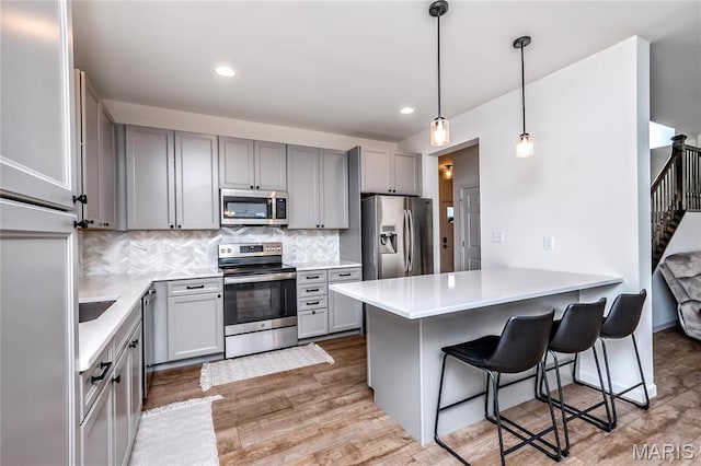 kitchen featuring appliances with stainless steel finishes, gray cabinetry, a peninsula, and recessed lighting