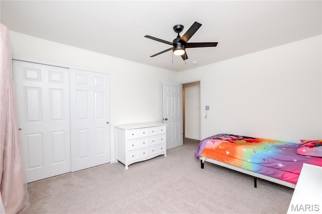 bedroom featuring light colored carpet, a closet, and a ceiling fan