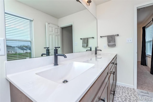 bathroom with double vanity and baseboards