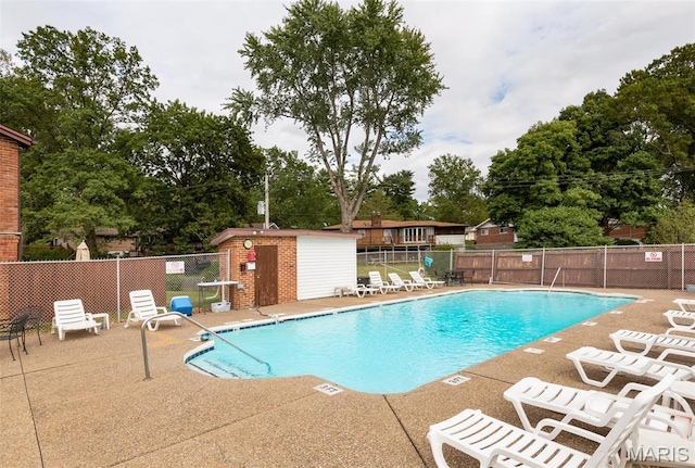 community pool featuring fence, a patio, and view of scattered trees