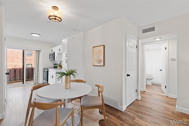 dining space with light wood-style flooring and baseboards