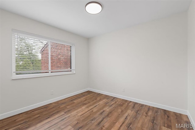 unfurnished room with baseboards and hardwood / wood-style flooring