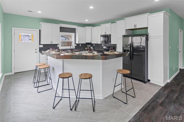 731 Dugger St, Bethalto, IL 62010 - kitchen featuring black refrigerator with ice dispenser, electric range, a kitchen bar, white cabinets, and a kitchen island