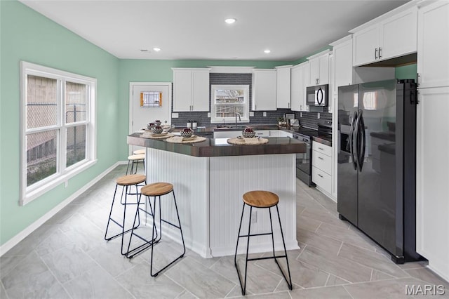 731 Dugger St, Bethalto, IL 62010 - kitchen featuring black appliances, dark countertops, a breakfast bar area, white cabinetry, and a sink