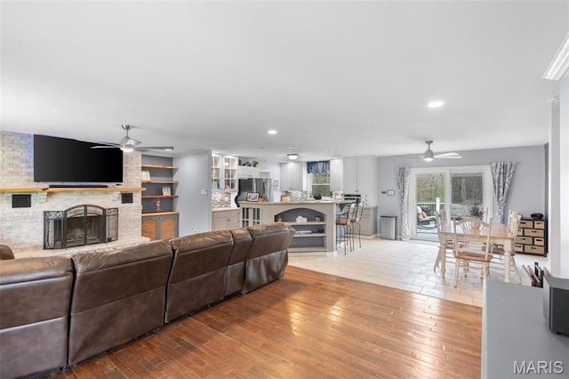 living room featuring ceiling fan, a brick fireplace, hardwood / wood-style flooring, and recessed lighting