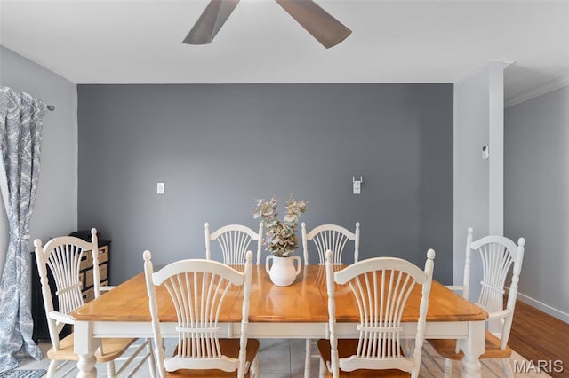 dining room with ceiling fan, wood finished floors, baseboards, and crown molding