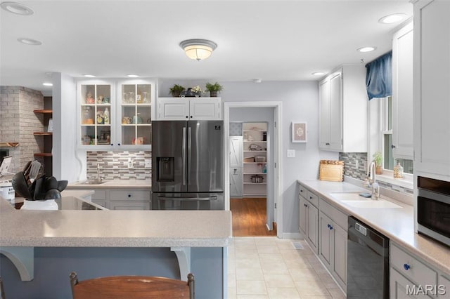 kitchen with stainless steel appliances, a sink, tasteful backsplash, light countertops, and recessed lighting