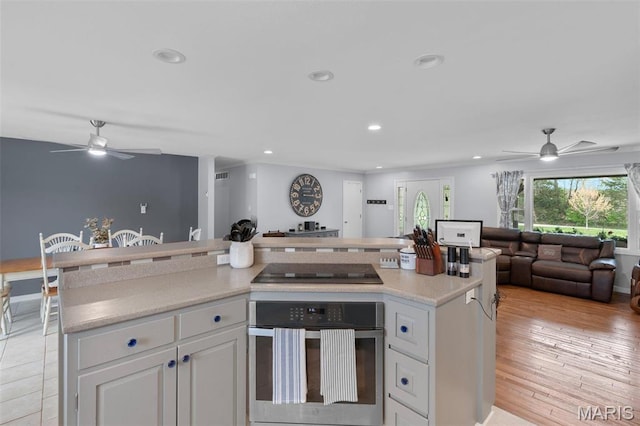 kitchen featuring stainless steel oven, ceiling fan, black electric stovetop, open floor plan, and recessed lighting