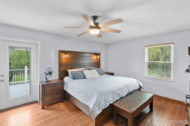 bedroom featuring access to outside, light wood-style floors, a textured ceiling, and ceiling fan