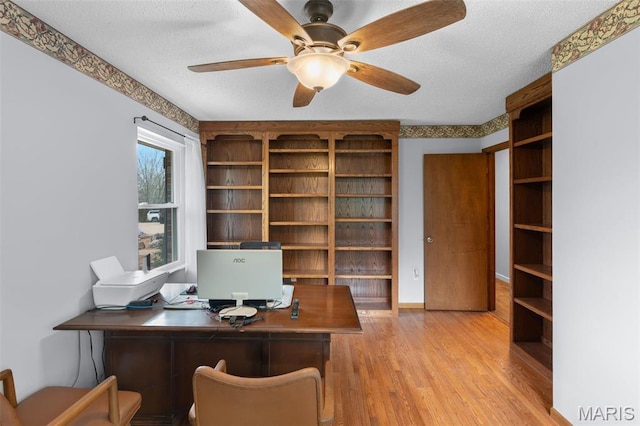 unfurnished office featuring light wood-style floors, a textured ceiling, and ceiling fan