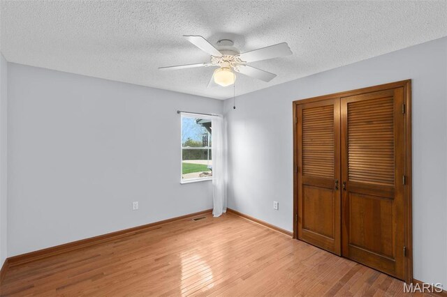 unfurnished bedroom featuring light wood-type flooring, a textured ceiling, a closet, baseboards, and ceiling fan