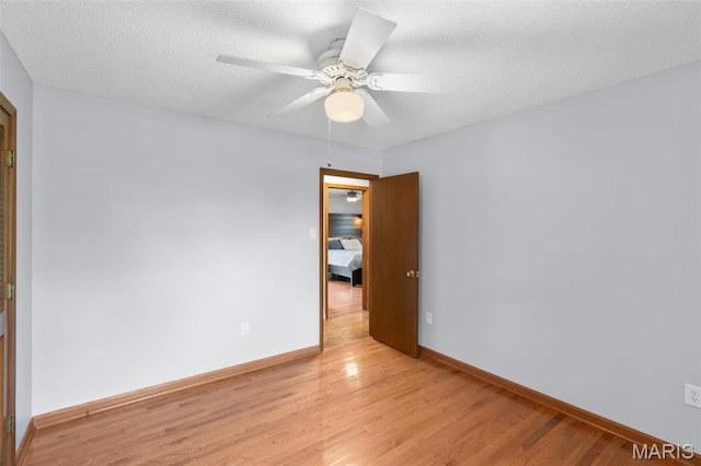 spare room with light wood finished floors, baseboards, ceiling fan, and a textured ceiling