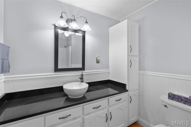 bathroom featuring a wainscoted wall, vanity, and toilet
