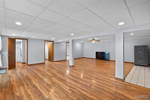 finished below grade area with wood finished floors, a drop ceiling, baseboards, and recessed lighting
