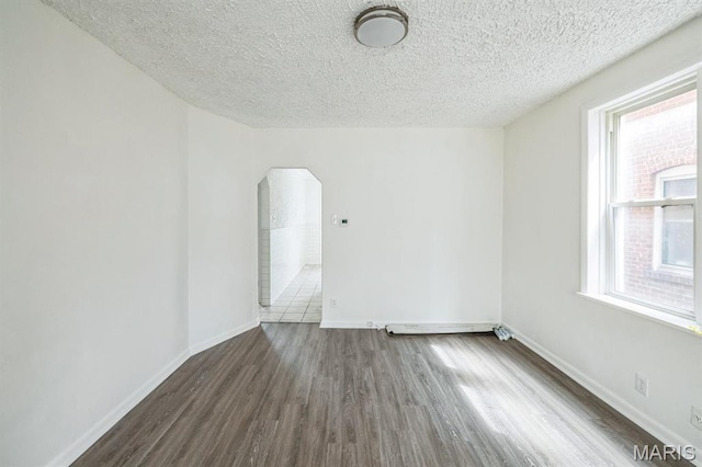 4931 Mardel Ave, Saint Louis, MO 63109 - empty room with arched walkways, wood finished floors, a textured ceiling, and baseboards