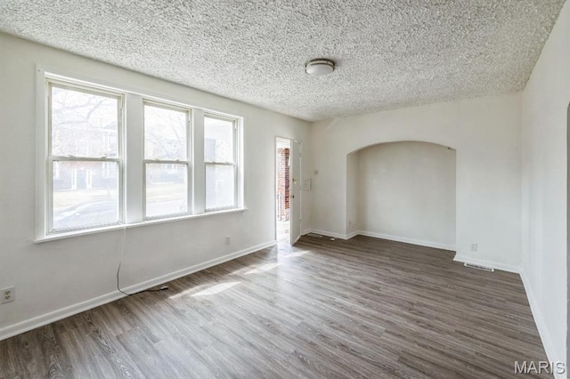 4931 Mardel Ave, Saint Louis, MO 63109 - empty room with arched walkways, wood finished floors, a textured ceiling, and baseboards
