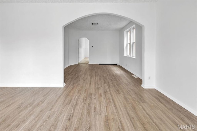 4931 Mardel Ave, Saint Louis, MO 63109 - empty room featuring arched walkways, wood finished floors, baseboards, and a textured ceiling