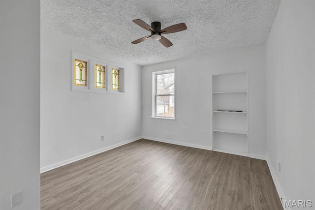 4931 Mardel Ave, Saint Louis, MO 63109 - unfurnished room with a textured ceiling, ceiling fan, wood finished floors, built in shelves, and baseboards